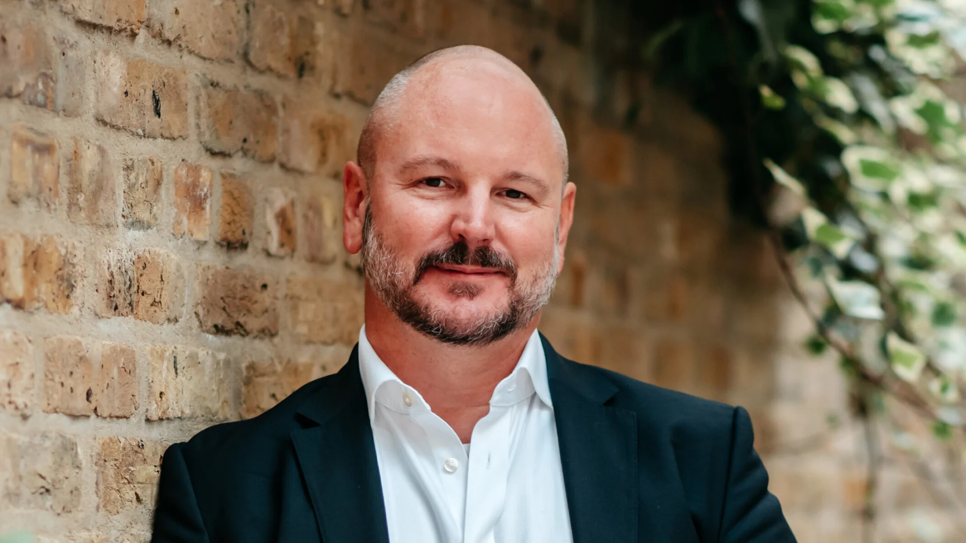 The profile image of DACS CEO, Christian Zimmermann. A white man in a suit in front of a brick wall.