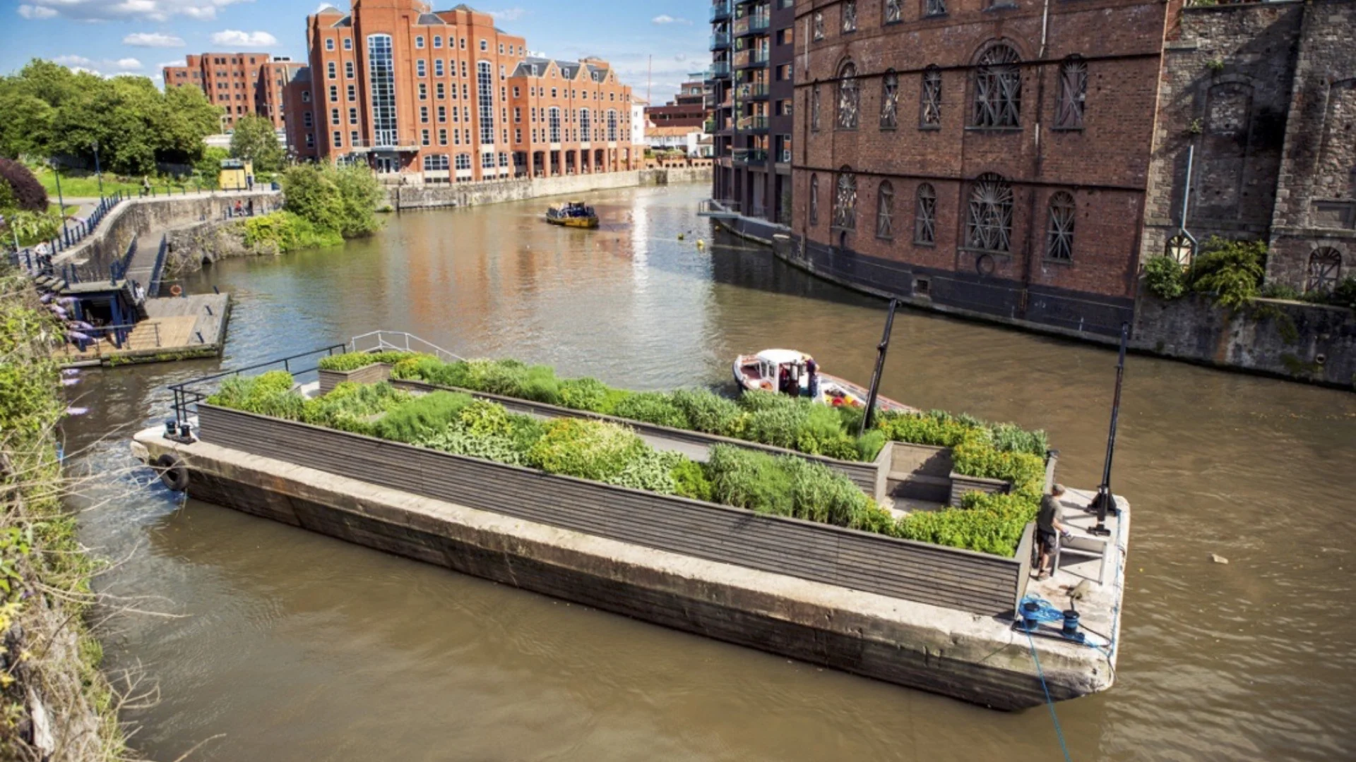 An overview of a canal in front of some brick buildings and some gardens
