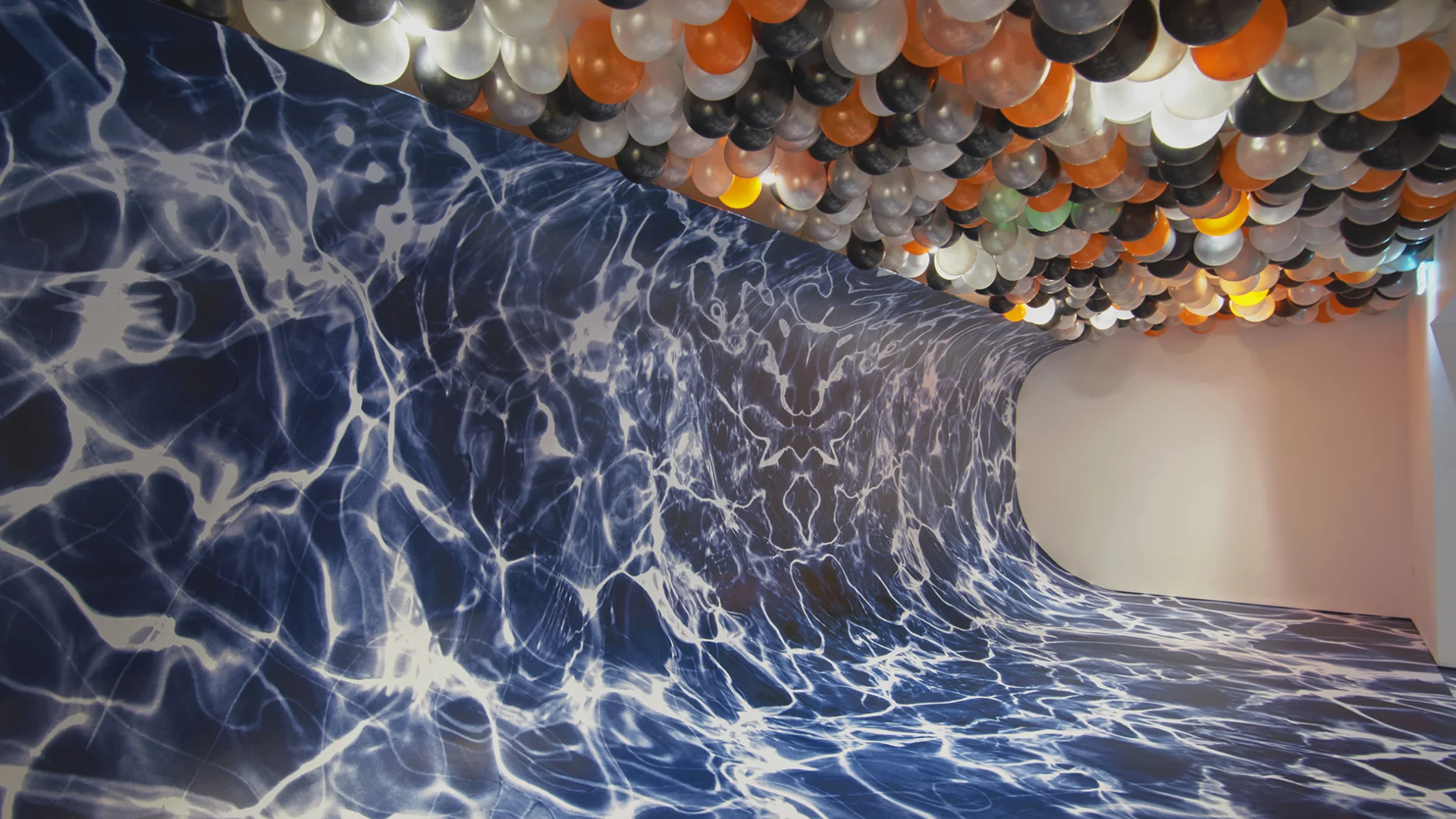 A wallpaper depicting waved covering a wall in a wave shape and colourful balloons covering the ceiling