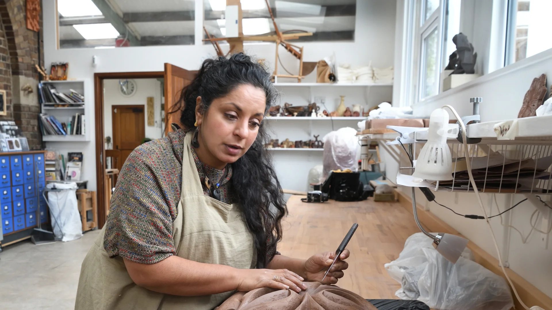 A woman in an art studio working on geometric clay sculptures