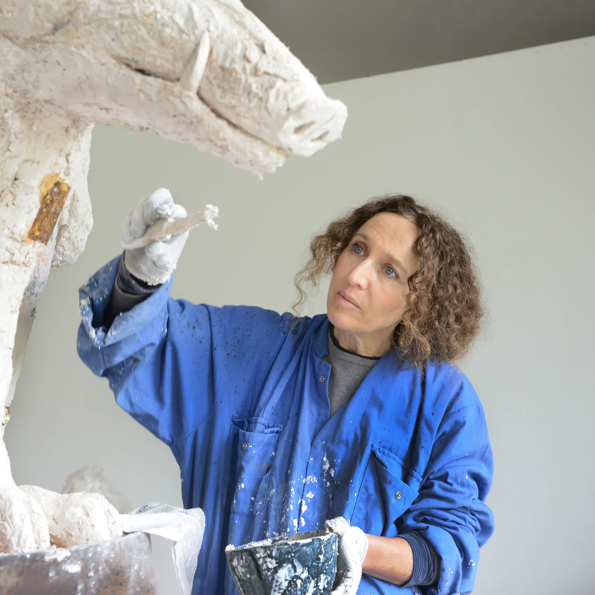 A white woman sculpting a horse