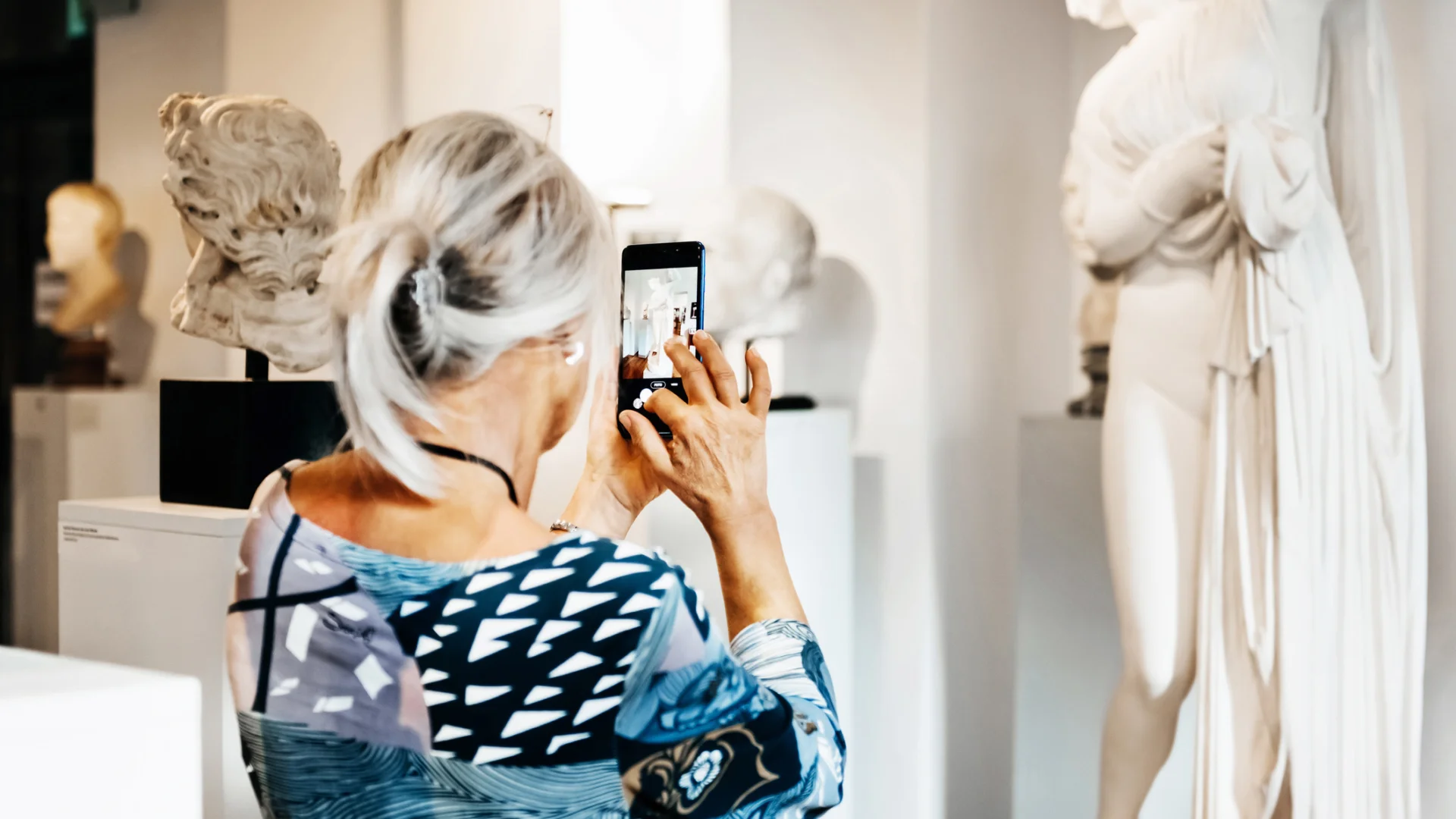 Women Taking Picture Of Classical Sculpture