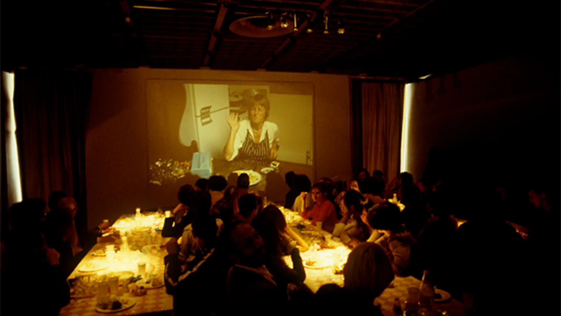 Group having dinner watching a cook on a large screen