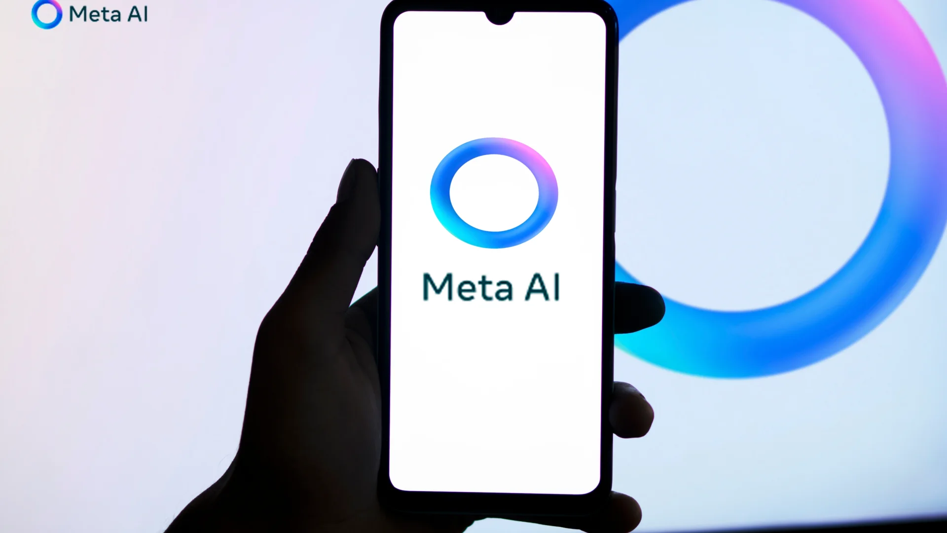 A close up of a smartphone with the words 'Meta AI' shown on it and a blue circle.