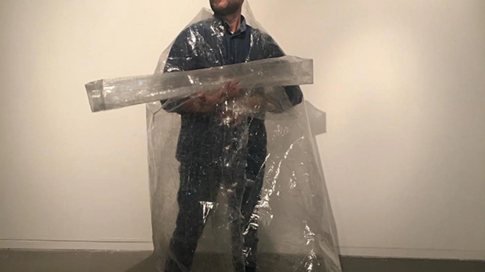 Man covered in clear plastic holding a clear plastic beam