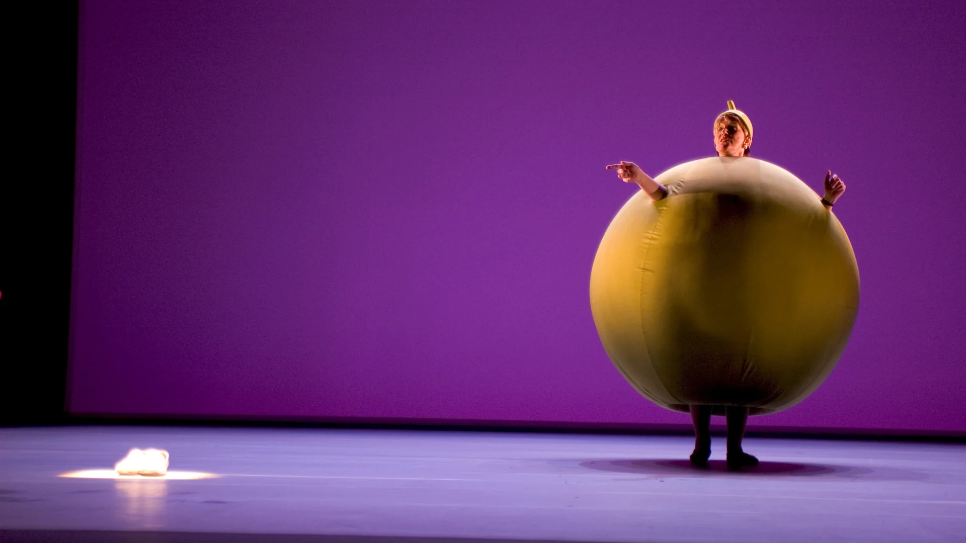 Person on a stage in a large orange ball costume