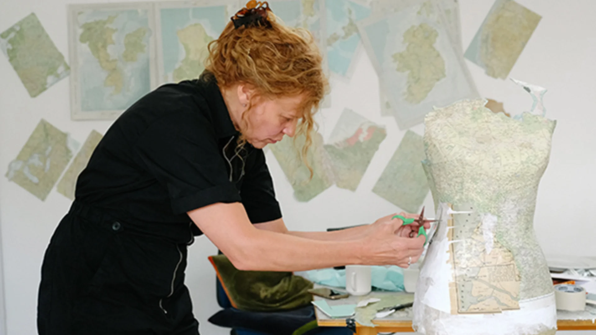 Lady working on a dress mannequin using maps as material