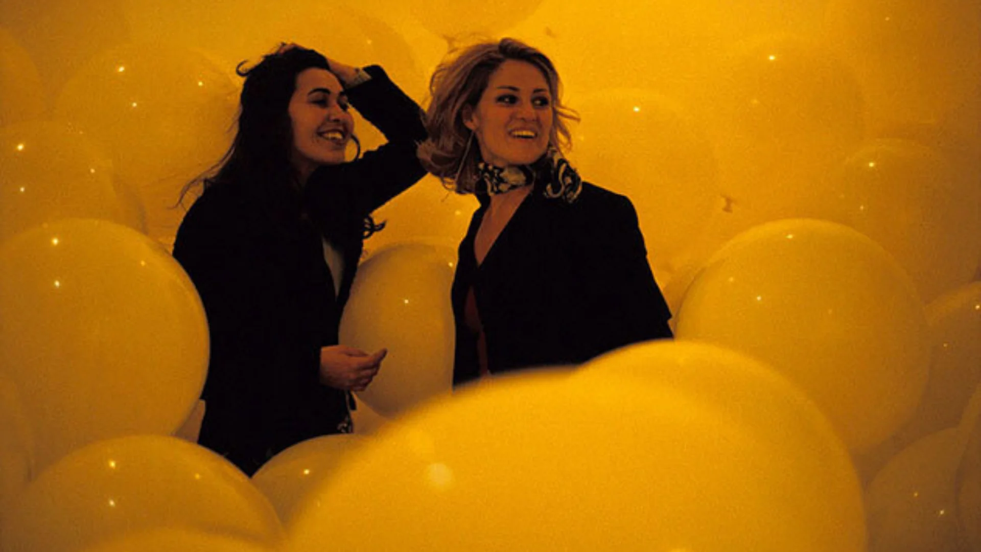 Two women smiling surrounded by orange balloons