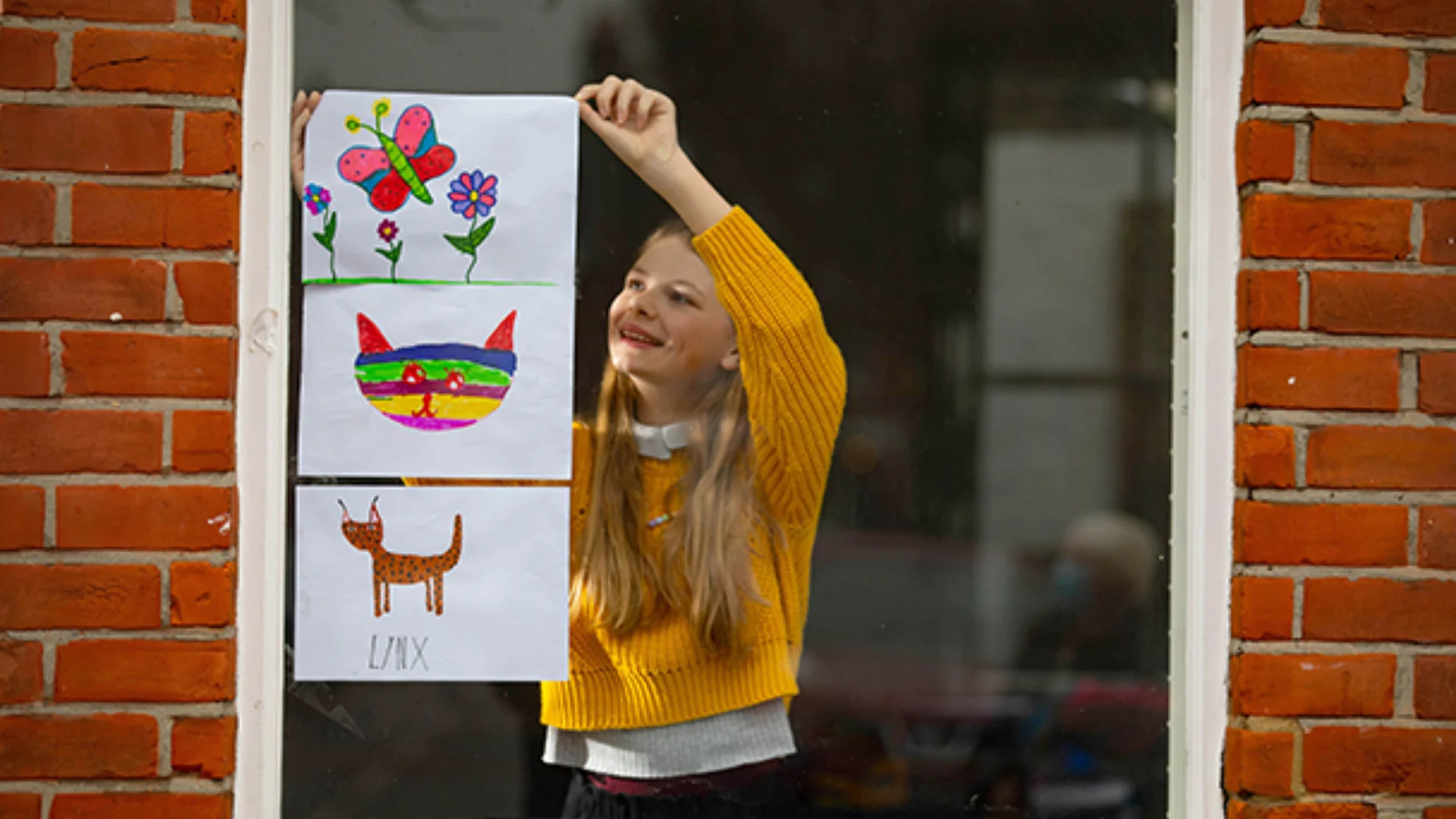 A child's artwork depicting animals is being put up on the house window by  a child