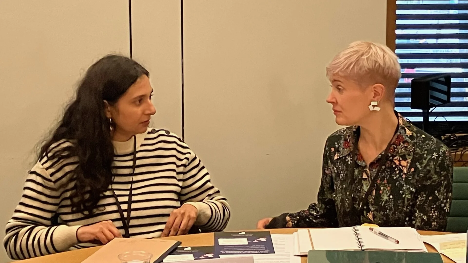 Two women sitting and discussing in front of a table