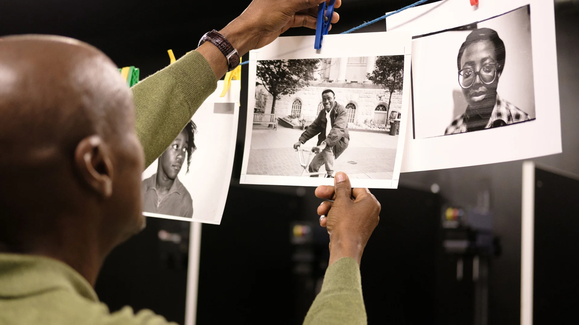a photograph showing a man hanging black and white photographic prints to dry in a studio.